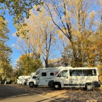Wohnmobile parken auf einem herbstlichen Stellplatz, umgeben von bunten Bäumen und Laub. Ein Schild weist auf den Wohnmobilstellplatz hin., © Stadtmarketing Göppingen