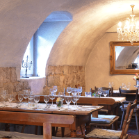 Cozy dining room with covered wooden tables, chandelier, mirror and rustic stone walls. Elegant atmosphere with candles and flowers., &copy; FreCla Gastronomiebetriebe GmbH