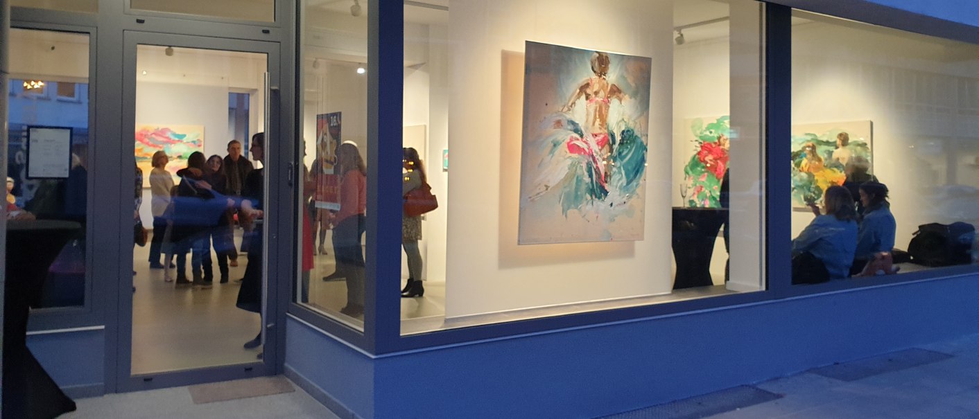 Eine Galerie mit großen Fenstern zeigt bunte Gemälde. Menschen stehen und betrachten die Kunstwerke im Inneren., © EXOgallery Contemporary and New Media Art Eine Galerie mit großen Fenstern zeigt bunte Gemälde. Menschen stehen und betrachten die Kunstwerke im Inneren., © EXOgallery Contemporary and New Media Art