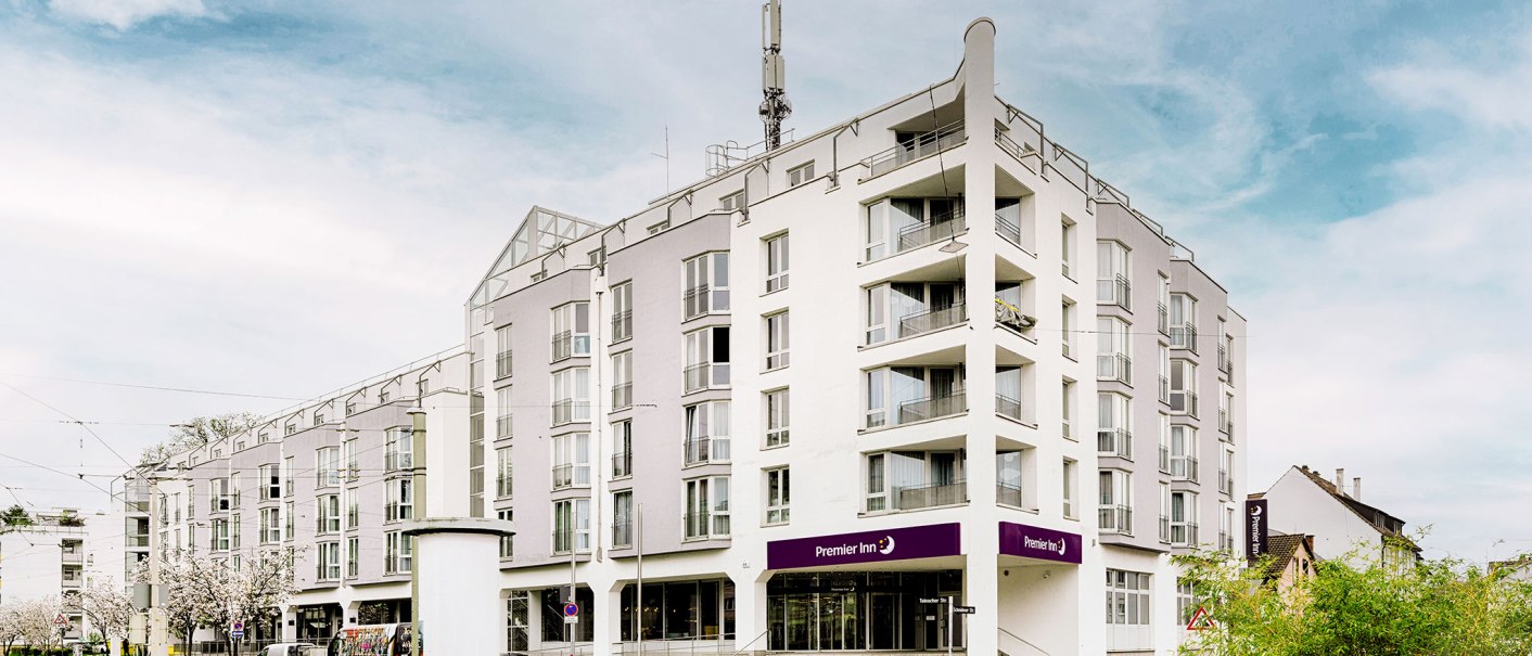 Modernes Hotelgeb&auml;ude mit mehreren Stockwerken, Balkonen und einem Premier Inn Schild. Der Himmel ist leicht bew&ouml;lkt., &copy; Premier Inn Germany