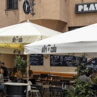 Outdoor area of a caf&eacute; called Platzhirsch with parasols and guests. People sit at tables and enjoy drinks., &copy; SMG, Sarah Schmid
