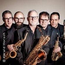 Fünf Männer mit Saxophonen posieren in schwarzer Kleidung vor einem neutralen Hintergrund., © links im Bild Fünf Männer mit Saxophonen posieren in schwarzer Kleidung vor einem neutralen Hintergrund., © links im Bild