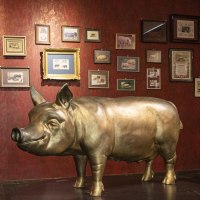 A room in the Stuttgart Pig Museum with a large pig sculpture and numerous framed pictures on a red wall., &copy; Stuttgart-Marketing GmbH, Sarah Schmid