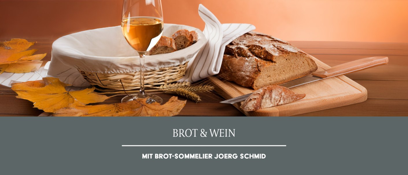 A glass of white wine sits next to a basket of bread and a loaf of bread on a cutting board. Fall leaves adorn the scene., &copy; Weinmanufaktur Stuttgart eG