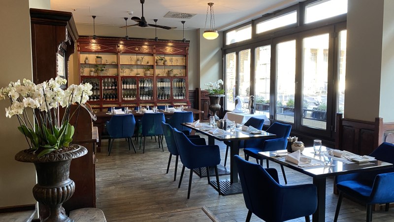 Elegant restaurant with blue chairs, wooden floor and large windows. Orchids and a display case with bottles decorate the room., &copy; Steigenberger Hotels GmbH