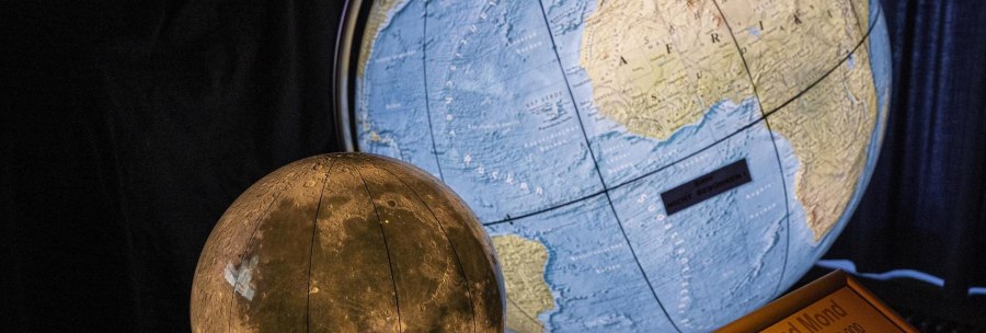 A globe of the earth and a model of the moon in the Carl-Zeiss Planetarium Stuttgart, with an information board about scale and distance., &copy; Stuttgart-Marketing GmbH, Sarah Schmid