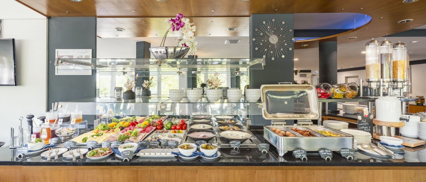 A breakfast buffet with a selection of dishes such as fruit, cold cuts, eggs and muesli in a modern restaurant., © Plaza INN Stuttgart-Filderstadt A breakfast buffet with a selection of dishes such as fruit, cold cuts, eggs and muesli in a modern restaurant., © Plaza INN Stuttgart-Filderstadt