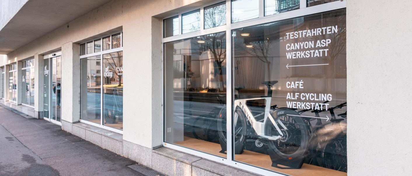 Ein Fahrradgesch&auml;ft mit gro&szlig;en Fenstern zeigt Fahrr&auml;der im Schaufenster. Auf der Scheibe steht 'Testfahrten, Canyon ASP Werkstatt, Caf&eacute;, Alf Cycling Werkstatt'., &copy; Stuttgart-Marketing GmbH, Sarah Schmid