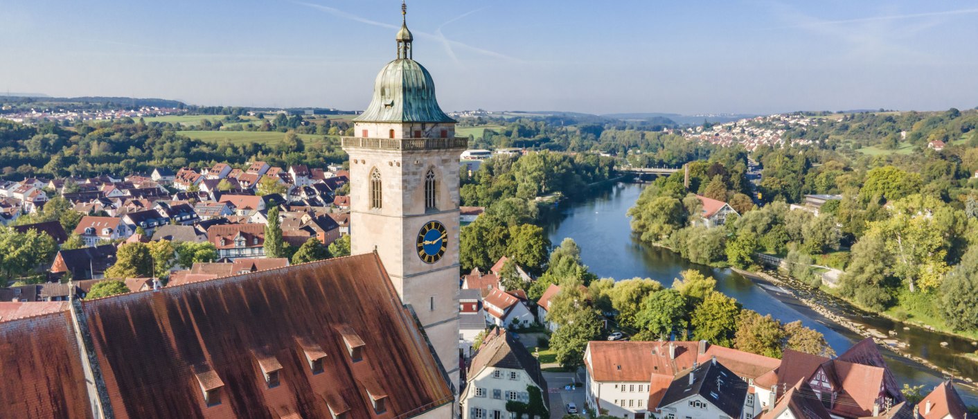 Drone view of the town church on the Neckar, surrounded by red roofs and green countryside. The river meanders through the city., © Stadplanungsamt Stadt Nürtingen; artismedia GmbH/ Olaf Kühl Drone view of the town church on the Neckar, surrounded by red roofs and green countryside. The river meanders through the city., © Stadplanungsamt Stadt Nürtingen; artismedia GmbH/ Olaf Kühl