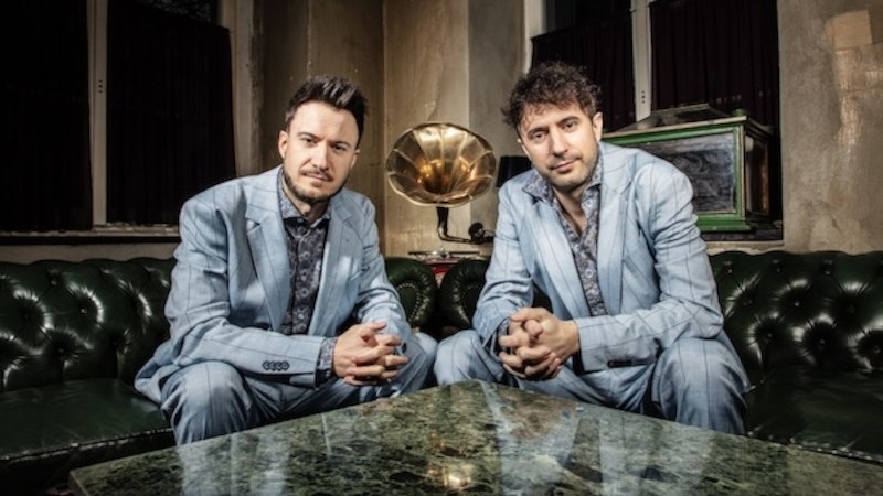 Two men stand opposite each other holding a violin and a melodica. They look at each other seriously., &copy; Renitenztheater Stuttgart e.V.