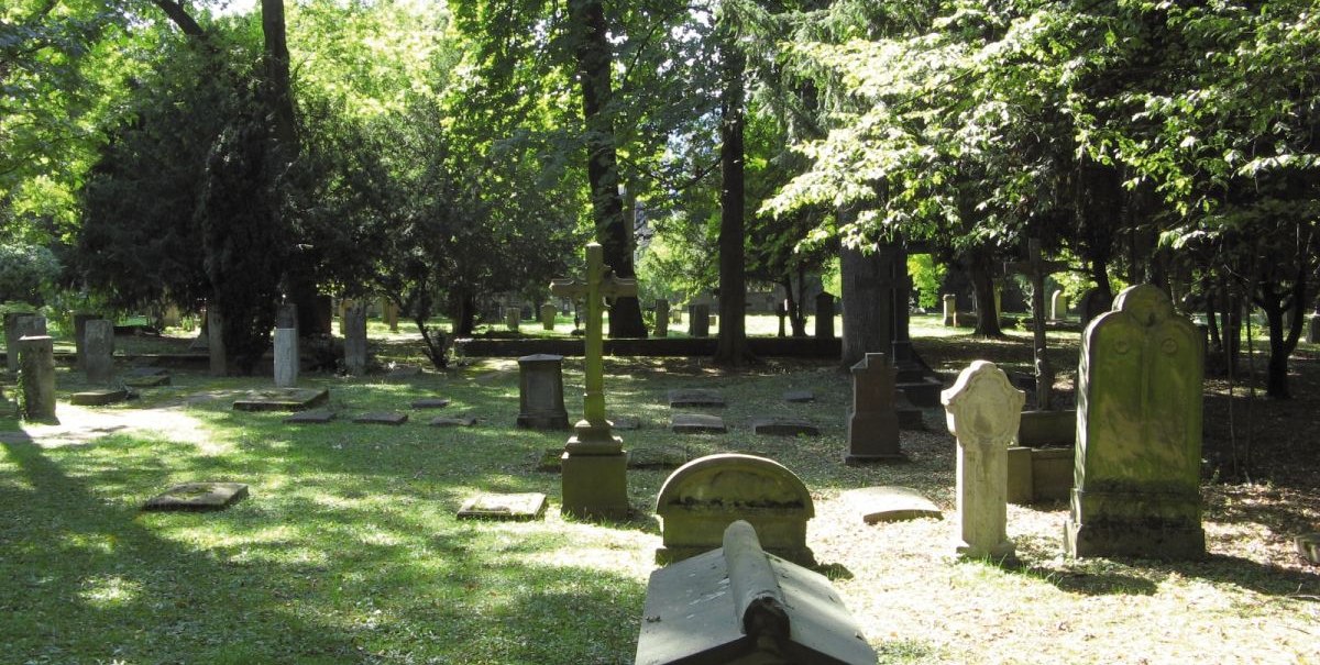 Gräber auf dem Hoppenlaufriedhof, umgeben von Bäumen. Sonnenlicht fällt durch das Blätterdach und beleuchtet die Grabsteine und den Boden., © Stuttgart-Marketing GmbH Gräber auf dem Hoppenlaufriedhof, umgeben von Bäumen. Sonnenlicht fällt durch das Blätterdach und beleuchtet die Grabsteine und den Boden., © Stuttgart-Marketing GmbH