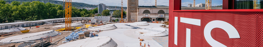 View of a construction site with several cranes and a red building with the inscription 'ITS' in the foreground., © Thomas Niedermüller