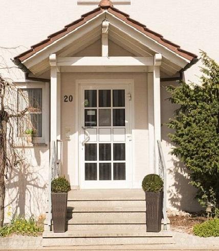 Eingang eines Gebäudes mit weißer Tür, Vordach und zwei Pflanzen in Töpfen. Hausnummer 20 ist sichtbar., © Hotel Engelhof