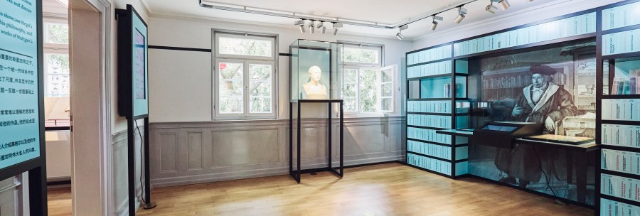 Interior view of the permanent exhibition in the Hegel House. A bust stands in a glass case, next to it a large wall display with historical illustrations., &copy; JuliaOchs