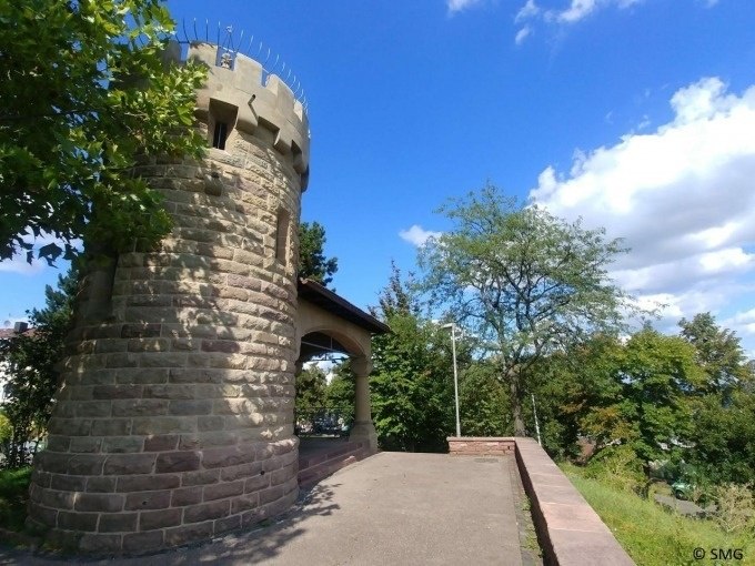 Ein steinerner Turm mit Zinnen steht neben einem Weg, umgeben von B&auml;umen unter blauem Himmel., &copy; Stuttgart Marketing GmbH