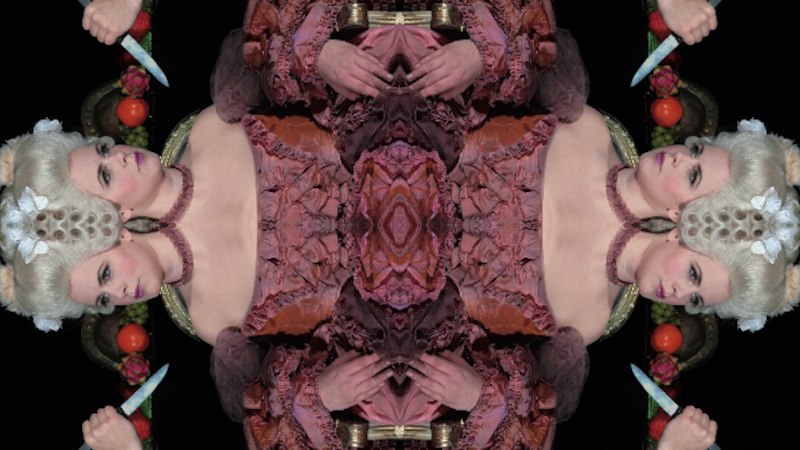 Symmetrisches Bild mit barock gekleideter Frau, weißer Perücke und Messer in der Hand. Dekorative Elemente und Früchte im Hintergrund., © Wilhelma Theater Symmetrisches Bild mit barock gekleideter Frau, weißer Perücke und Messer in der Hand. Dekorative Elemente und Früchte im Hintergrund., © Wilhelma Theater