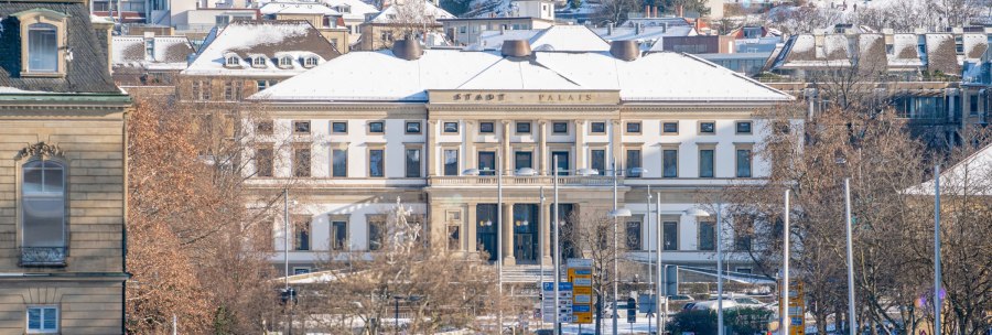 The StadtPalais in Stuttgart can be seen in winter, with a snow-covered roof and surrounding buildings. Trees without leaves in the foreground., © SMG Thomas Niedermüller