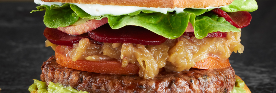 A juicy burger with lettuce, tomato, onions, beet and avocado on a soft bun., © MAREDO