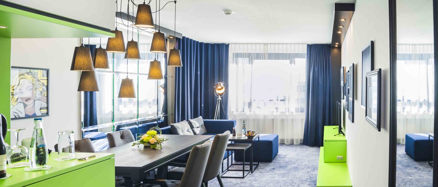 Modern suite with dining table, sofa area, art on the wall and stylish lighting. Large windows with blue curtains let in plenty of light., &copy; Chandler Photography