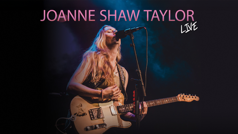 Joanne Shaw Taylor performt live auf der Bühne mit Gitarre und Mikrofon. Der Hintergrund ist dunkel mit bunten Lichteffekten., © links im Bild Joanne Shaw Taylor performt live auf der Bühne mit Gitarre und Mikrofon. Der Hintergrund ist dunkel mit bunten Lichteffekten., © links im Bild