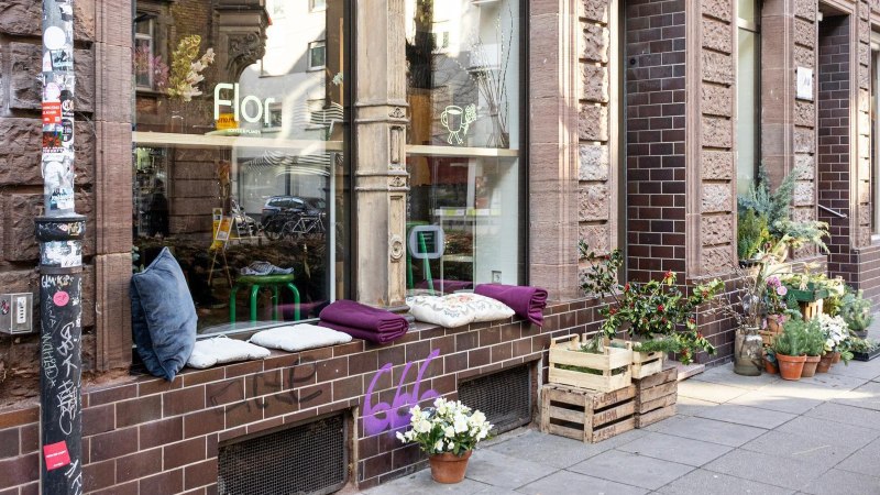 A cozy caf&eacute; with plants and cushions on the windowsill. A sign advertises coffee and cookies. The fa&ccedil;ade is made of brown bricks., &copy; Stuttgart-Marketing GmbH, Sarah Schmid