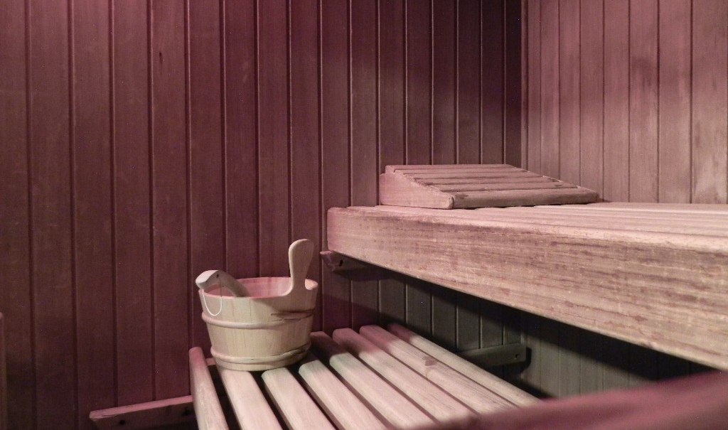 Interior view of a sauna with wooden benches, a wooden bucket and a wooden backrest. The walls are made of wooden panels., © Hotel Gloria GmbH Restaurant Möhringer Hexle Interior view of a sauna with wooden benches, a wooden bucket and a wooden backrest. The walls are made of wooden panels., © Hotel Gloria GmbH Restaurant Möhringer Hexle