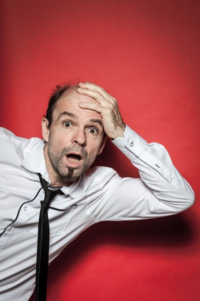 Mann in weißem Hemd und schwarzer Krawatte vor rotem Hintergrund, hält sich mit erstaunter Miene die Stirn., © Renitenztheater Stuttgart e.V. Mann in weißem Hemd und schwarzer Krawatte vor rotem Hintergrund, hält sich mit erstaunter Miene die Stirn., © Renitenztheater Stuttgart e.V.