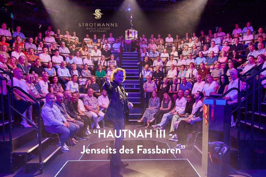 A magician performs in front of a full audience in the Strotmanns Magic Lounge Stuttgart. The room is atmospherically lit., © Strotmanns Magic Lounge A magician performs in front of a full audience in the Strotmanns Magic Lounge Stuttgart. The room is atmospherically lit., © Strotmanns Magic Lounge