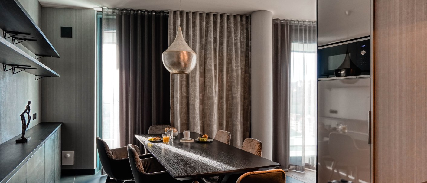 Modernes Esszimmer mit großem Tisch, eleganten Stühlen und einer stilvollen Hängelampe in einer Penthouse-Suite., © CLOUD N°7 APARTMENTS GmbH Modernes Esszimmer mit großem Tisch, eleganten Stühlen und einer stilvollen Hängelampe in einer Penthouse-Suite., © CLOUD N°7 APARTMENTS GmbH