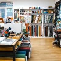 A fabric store with shelves full of colorful fabric rolls and sewing accessories. There are more materials on a table. Bags hang on the wall., © Lena Beck, Hummelkonig GbR, Stuttgart A fabric store with shelves full of colorful fabric rolls and sewing accessories. There are more materials on a table. Bags hang on the wall., © Lena Beck, Hummelkonig GbR, Stuttgart