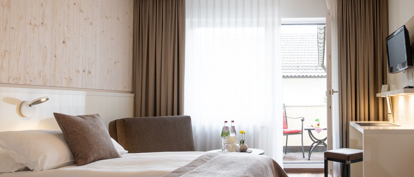 Modernes Hotelzimmer mit Doppelbett, Schreibtisch, Fernseher und Balkon. Dezente Farben und stilvolle Einrichtung schaffen eine gemütliche Atmosphäre., © Hotel Weinstadt Modernes Hotelzimmer mit Doppelbett, Schreibtisch, Fernseher und Balkon. Dezente Farben und stilvolle Einrichtung schaffen eine gemütliche Atmosphäre., © Hotel Weinstadt