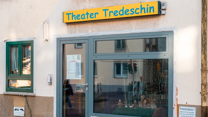 Eingang des Theater Tredeschin mit einem gelben Schild über der Tür. Ein Fenster mit Vorhang und ein kleiner Schaukasten sind sichtbar., © SMG, Sarah Schmid Eingang des Theater Tredeschin mit einem gelben Schild über der Tür. Ein Fenster mit Vorhang und ein kleiner Schaukasten sind sichtbar., © SMG, Sarah Schmid
