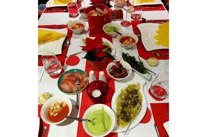 Ein Tisch mit verschiedenen Tapas, darunter Guacamole, Paprika und Brot. Festliche Dekoration mit roten Servietten und Weihnachtssternen., © Kultweine-Kochwelten-Kunstücke - Kochschule Sonja Lenz