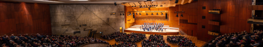 A large concert hall with a modern design, filled with spectators. An orchestra plays on the stage. The architecture is impressive., &copy; Holger Schneider
