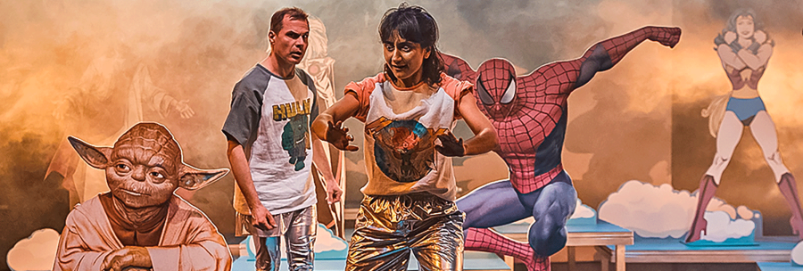Two people on a stage with Yoda, Spider-Man and Wonder Woman in the background. The scene looks imaginative and colorful., © JES, Alex Wunsch