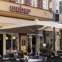 Ein Café mit dem Namen 'Weber' hat einen Außenbereich mit Tischen, Stühlen und Sonnenschirmen. Menschen sitzen und genießen Getränke., © SMG, Sarah Schmid Ein Café mit dem Namen 'Weber' hat einen Außenbereich mit Tischen, Stühlen und Sonnenschirmen. Menschen sitzen und genießen Getränke., © SMG, Sarah Schmid