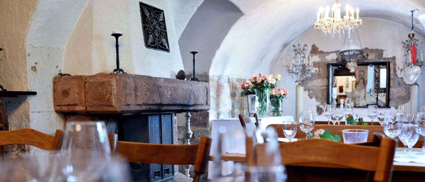 Eleganter Gastraum mit gewölbter Decke, Kamin, Kronleuchter und gedeckten Tischen. Blumenarrangements und Spiegel im Hintergrund., © FreCla Gastronomiebetriebe GmbH