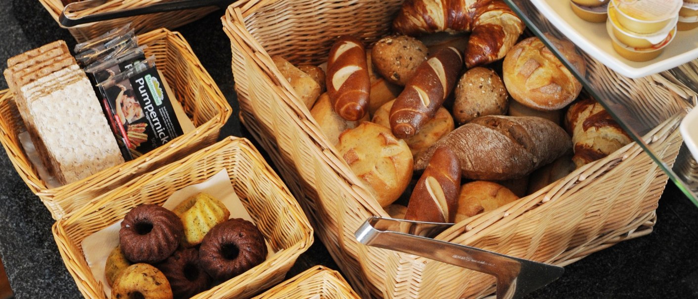 Verschiedene Brotsorten und Gebäck, darunter Croissants, Brötchen und Kuchen, in Körben auf einem Tisch arrangiert., © TOMAS Verschiedene Brotsorten und Gebäck, darunter Croissants, Brötchen und Kuchen, in Körben auf einem Tisch arrangiert., © TOMAS