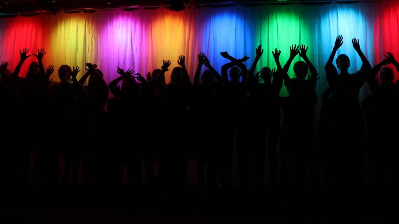 Schatten von Menschen mit erhobenen Armen vor einem regenbogenfarbenen Vorhang. Die Silhouetten sind dunkel, der Hintergrund leuchtet in bunten Farben., © Evang. Kirchengemeinde Rohr-Dürrlewang Schatten von Menschen mit erhobenen Armen vor einem regenbogenfarbenen Vorhang. Die Silhouetten sind dunkel, der Hintergrund leuchtet in bunten Farben., © Evang. Kirchengemeinde Rohr-Dürrlewang