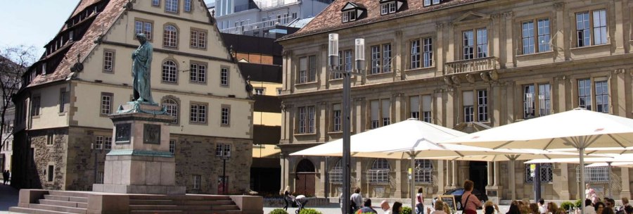 Schillerplatz in Stuttgart with a statue in the foreground, surrounded by historic buildings and people sitting under parasols., &copy; Stuttgart-Marketing GmbH