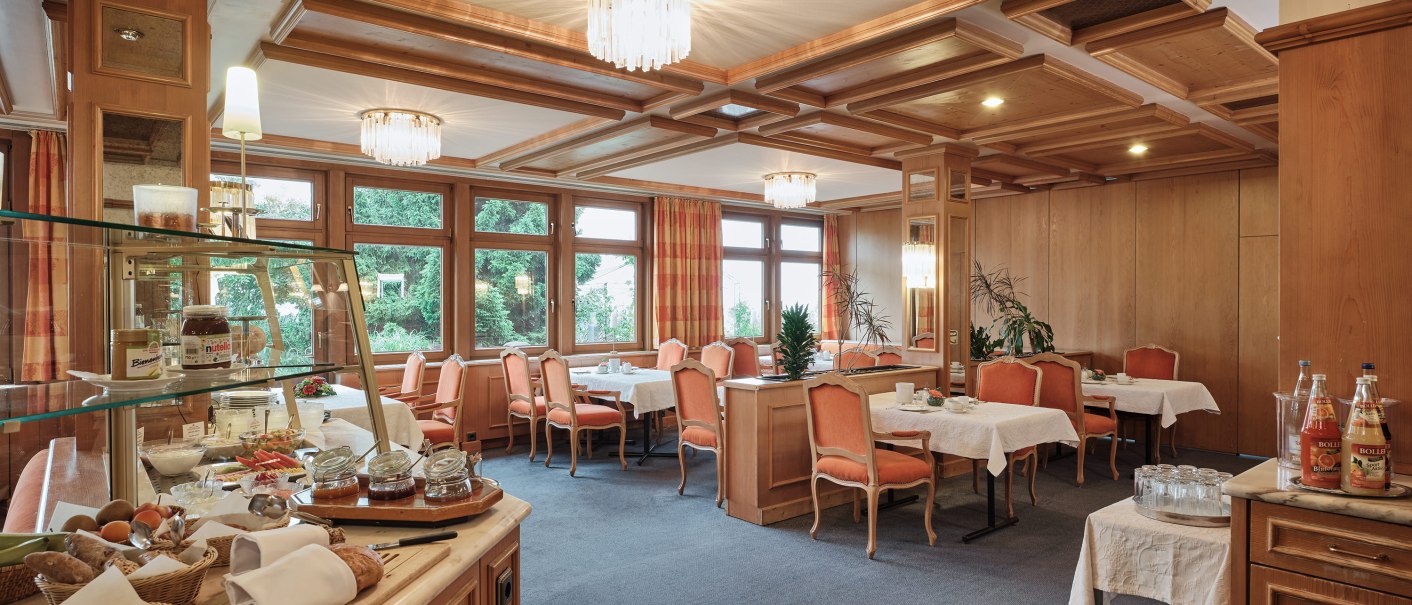 Eleganter Frühstücksraum mit gedeckten Tischen, Buffet mit Brot und Aufstrichen, Holzelementen und großen Fenstern., © Badhotel Restaurant Stauferland