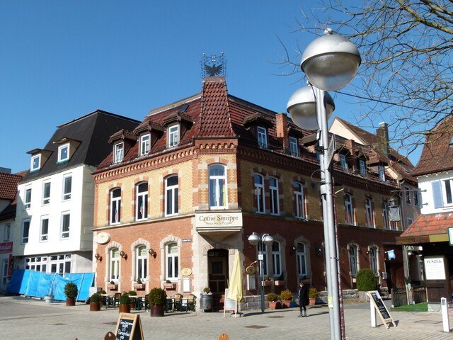 Historisches Gebäude mit rotem Ziegeldach und mehreren Fenstern, davor eine Straße mit Laternen und Menschen. Sonniger Tag., © AKZENT Hotel Torgauer Hof