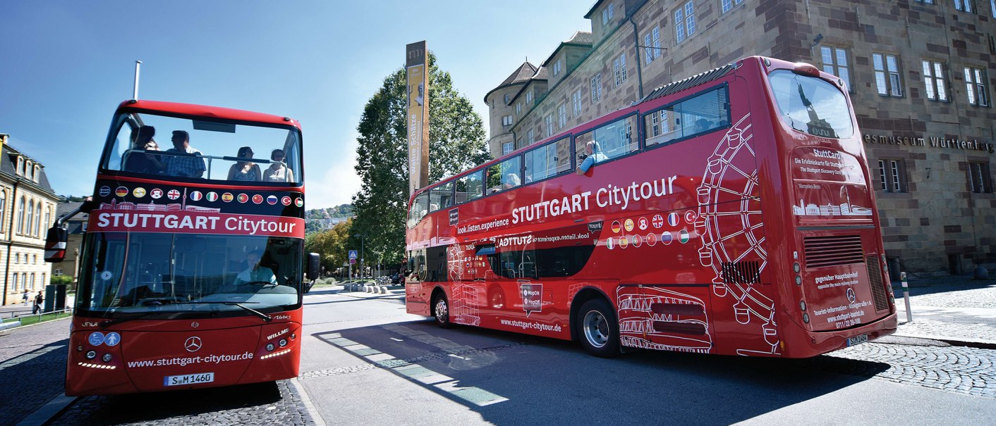 Zwei rote Doppeldeckerbusse der Stuttgart Citytour stehen vor dem Landesmuseum Württemberg. Menschen sitzen auf dem offenen Oberdeck., © Stuttgart-Marketing GmbH, Pierre Polak