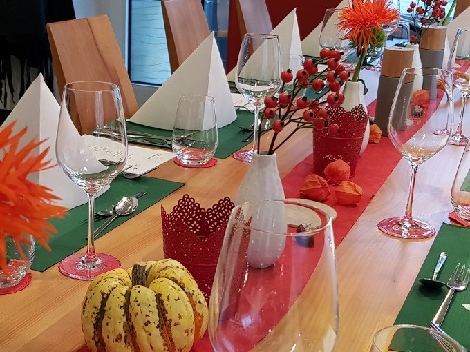 Ein festlich gedeckter Tisch mit Gläsern, weißen Servietten und herbstlicher Dekoration aus Kürbissen und roten Beeren., © Kultweine-Kochwelten-Kunstücke - Kochschule Sonja Lenz Ein festlich gedeckter Tisch mit Gläsern, weißen Servietten und herbstlicher Dekoration aus Kürbissen und roten Beeren., © Kultweine-Kochwelten-Kunstücke - Kochschule Sonja Lenz