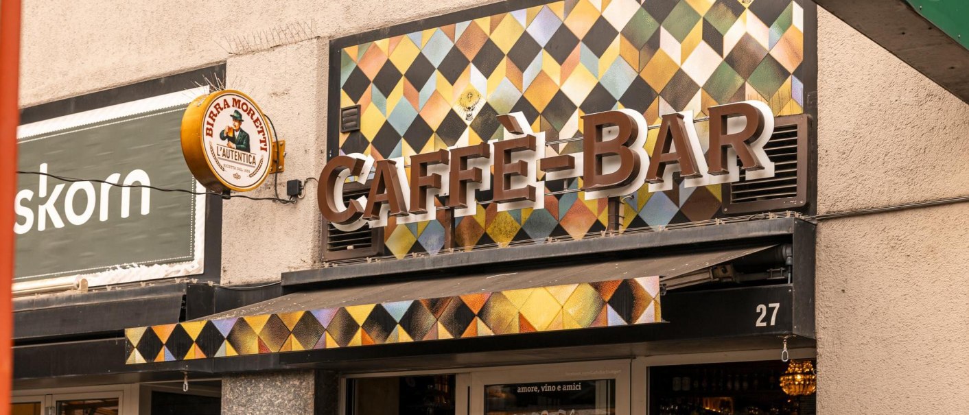 Fassade einer Caffè-Bar mit buntem Rautenmuster und einem Birra Moretti Schild an der Wand., © Stuttgart-Marketing GmbH, Sarah Schmid Fassade einer Caffè-Bar mit buntem Rautenmuster und einem Birra Moretti Schild an der Wand., © Stuttgart-Marketing GmbH, Sarah Schmid