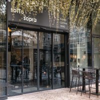 Entrance to a caf&eacute; with glass front and outdoor seating. Plants hang down from above. People are sitting inside. Sign with 'sotto sopra' visible., &copy; SMG Stuttgart Marketing GmbH - Sarah Schmid