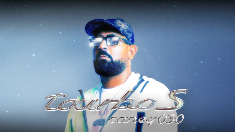 Ein Mann mit Bart und Brille, der eine Mütze trägt, steht vor einem sternenklaren Hintergrund. Der Schriftzug 'tourbo S caney030' ist prominent im Bild., © links im Bild Ein Mann mit Bart und Brille, der eine Mütze trägt, steht vor einem sternenklaren Hintergrund. Der Schriftzug 'tourbo S caney030' ist prominent im Bild., © links im Bild