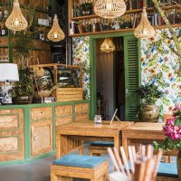 Cozy guest room with wooden furniture, colorful flowers, shelves full of bottles and books. Bright lamps and floral wallpaper create an inviting atmosphere., © Vietal Kitchen Cozy guest room with wooden furniture, colorful flowers, shelves full of bottles and books. Bright lamps and floral wallpaper create an inviting atmosphere., © Vietal Kitchen