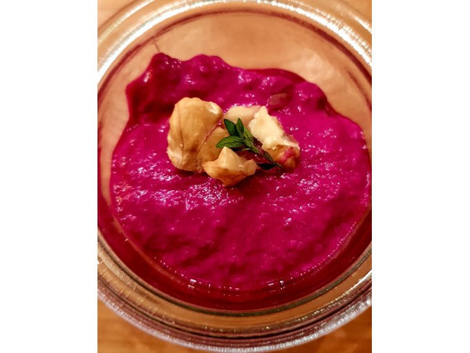Beet dip in a glass bowl, garnished with walnuts and a sprig of green herbs, on a wooden table., © Kultweine-Kochwelten-Kunstücke - Kochschule Sonja Lenz Beet dip in a glass bowl, garnished with walnuts and a sprig of green herbs, on a wooden table., © Kultweine-Kochwelten-Kunstücke - Kochschule Sonja Lenz