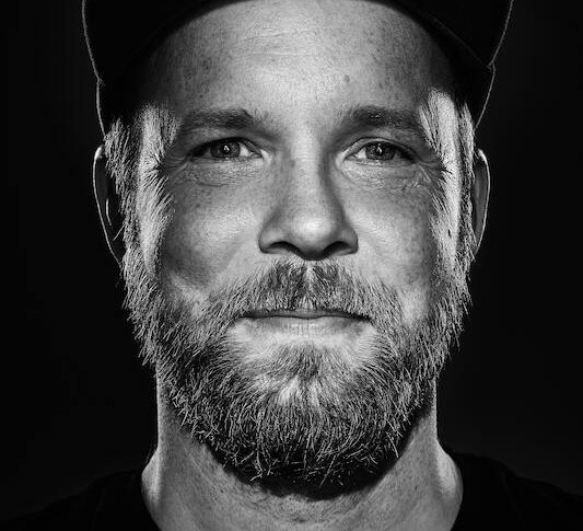 Schwarz-wei&szlig; Portr&auml;t eines Mannes mit Bart und M&uuml;tze, der direkt in die Kamera schaut., &copy; Rosenau Kultur e.V.